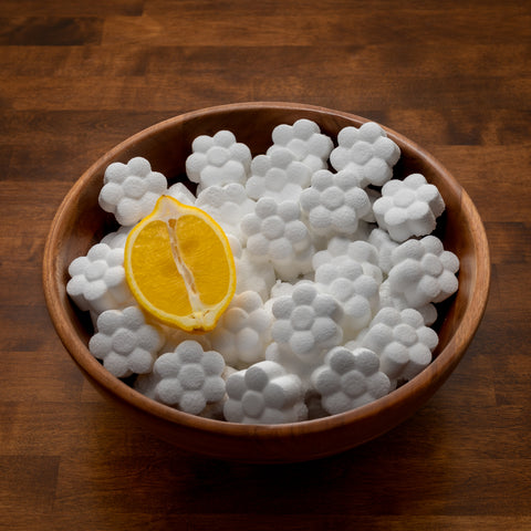 Lemon toilet cleaning pods in a wooden bowl with a lemon half